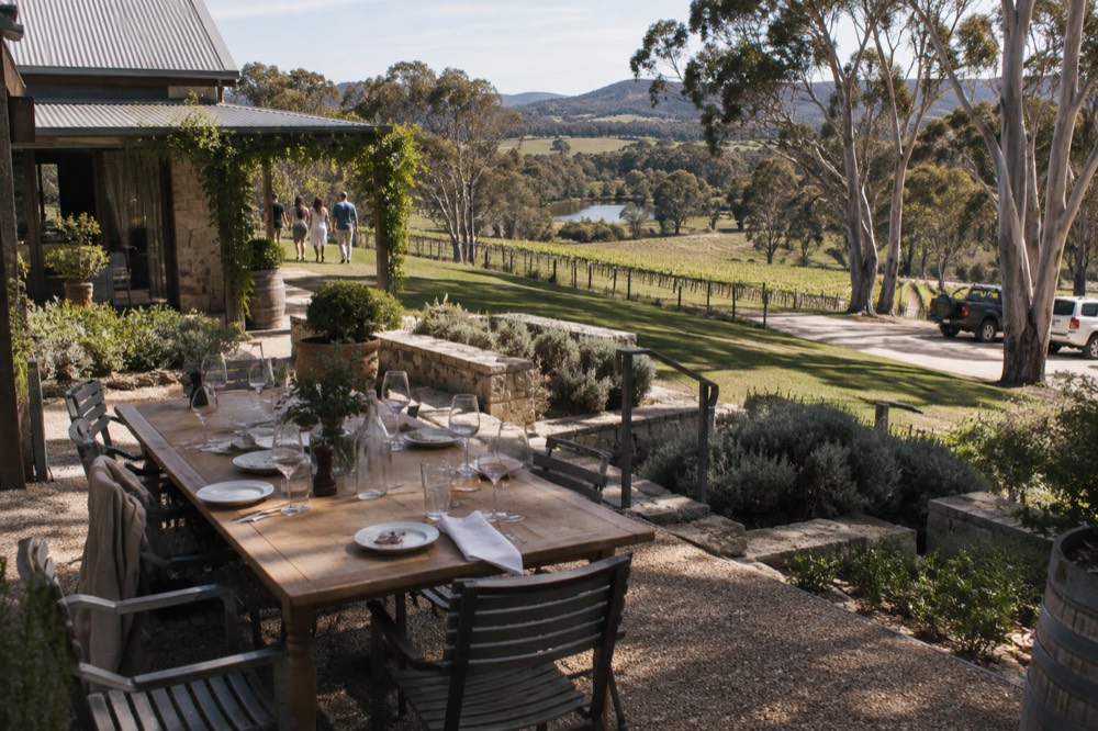 A long table set for lunch overlooking a vineyard valley