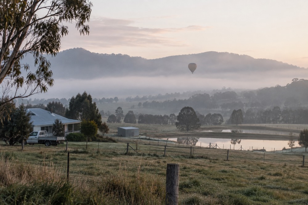Morning mist settled over valley farmland with forested ridges in the background