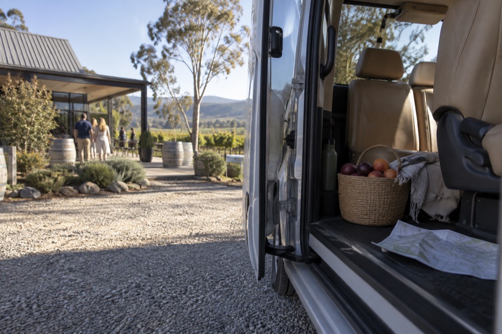 An open sliding door of a van revealing leather seats and a basket of local produce
