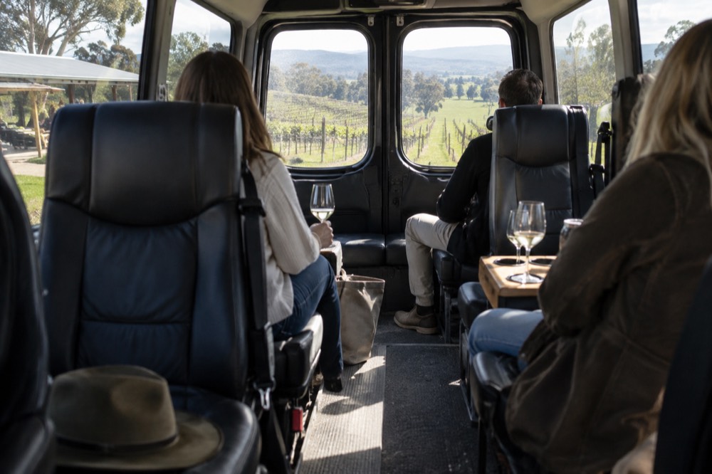 A van interior with individual seats facing each other over a narrow aisle