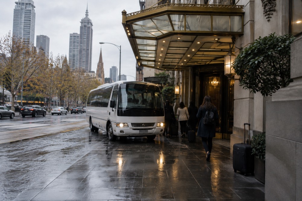 A hotel entrance canopy on a Melbourne CBD street with a small tour bus pulling up at the kerb
