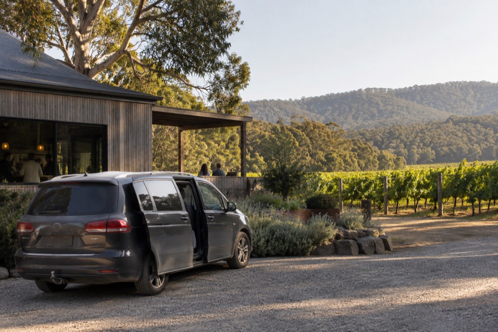 A private van parked beside a cellar door entrance among vineyards
